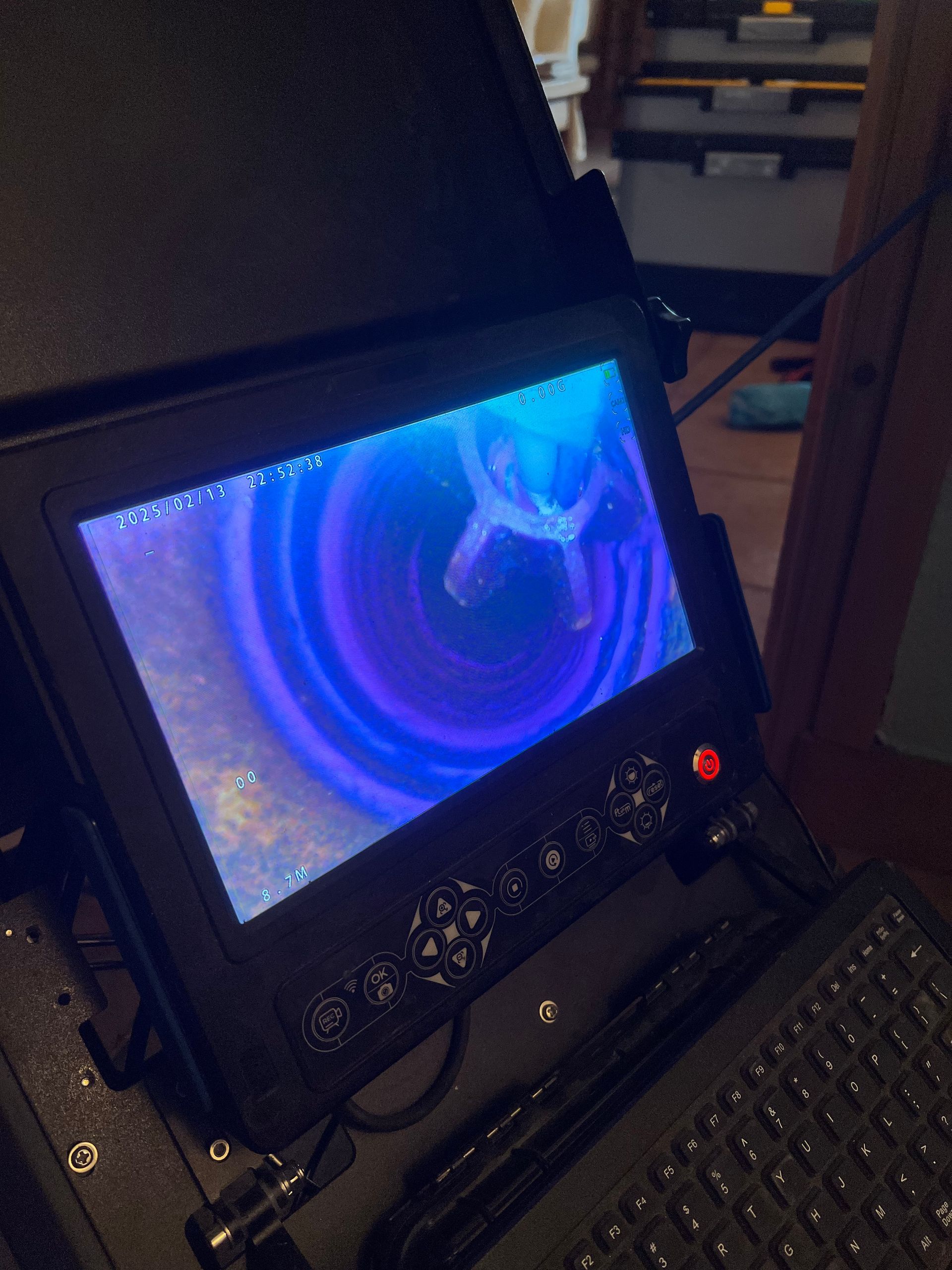 Écran affichant un tunnel bleu tourbillonnant, intégré dans un boîtier noir avec boutons et clavier.