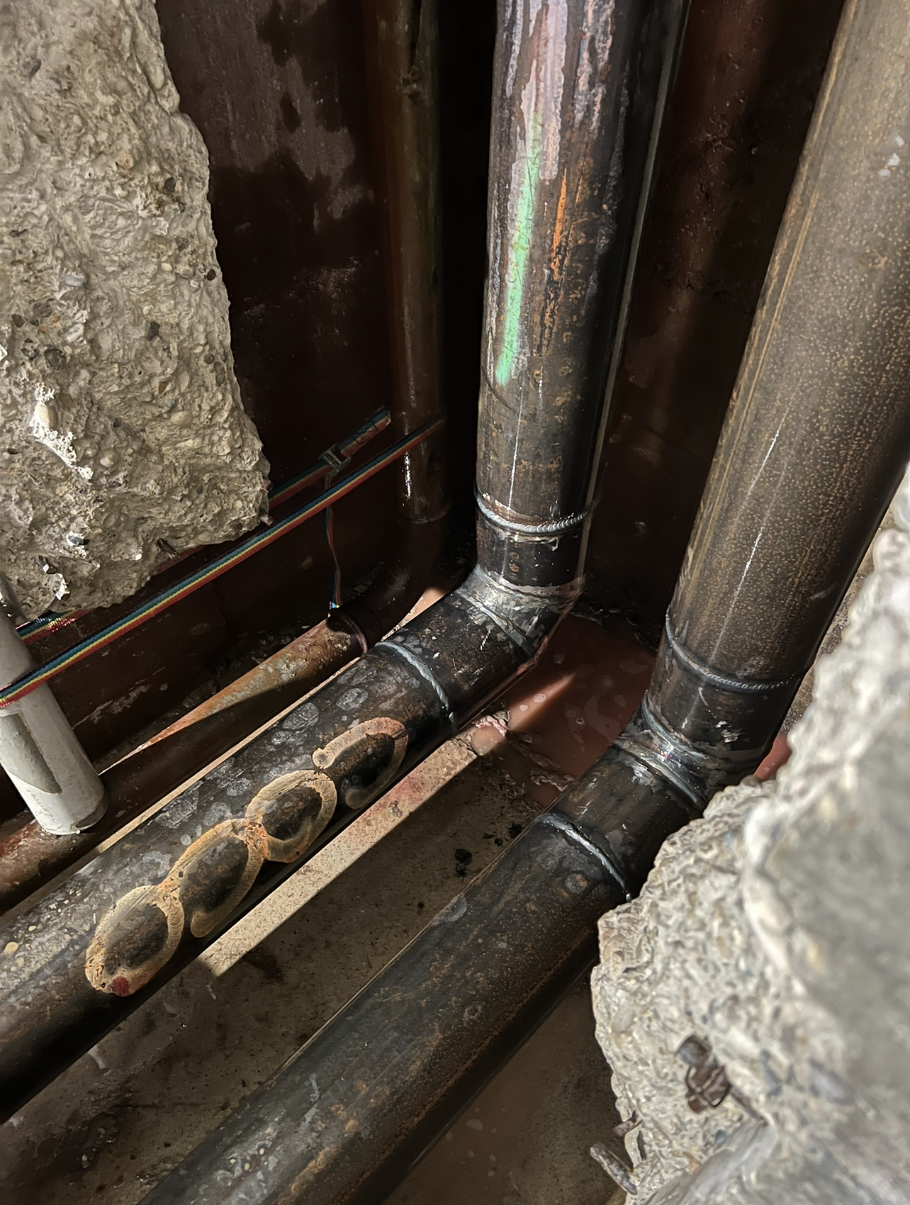 Tuyaux de cuivre avec coudes, encastrés dans un espace en béton.