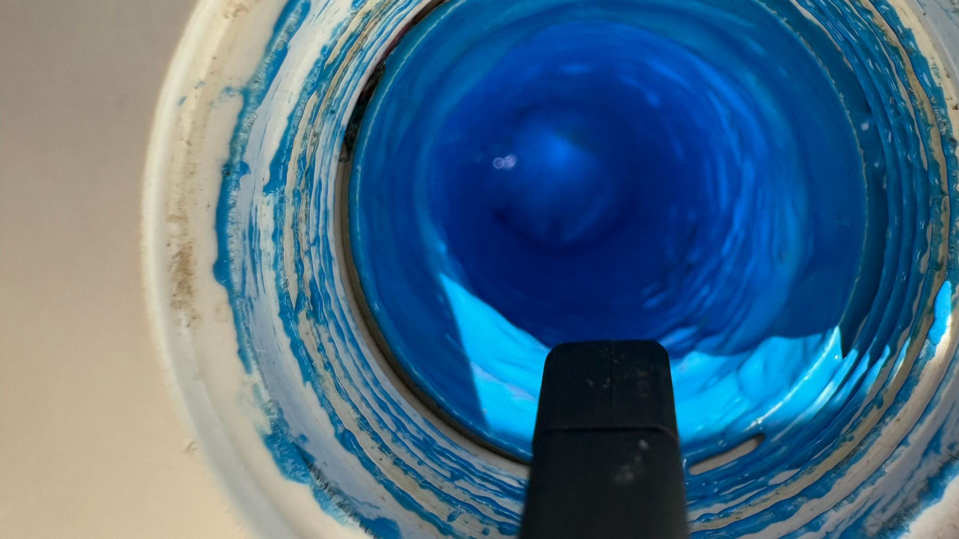 Vue à l'intérieur d'un tube peint en bleu avec un objet noir au fond.