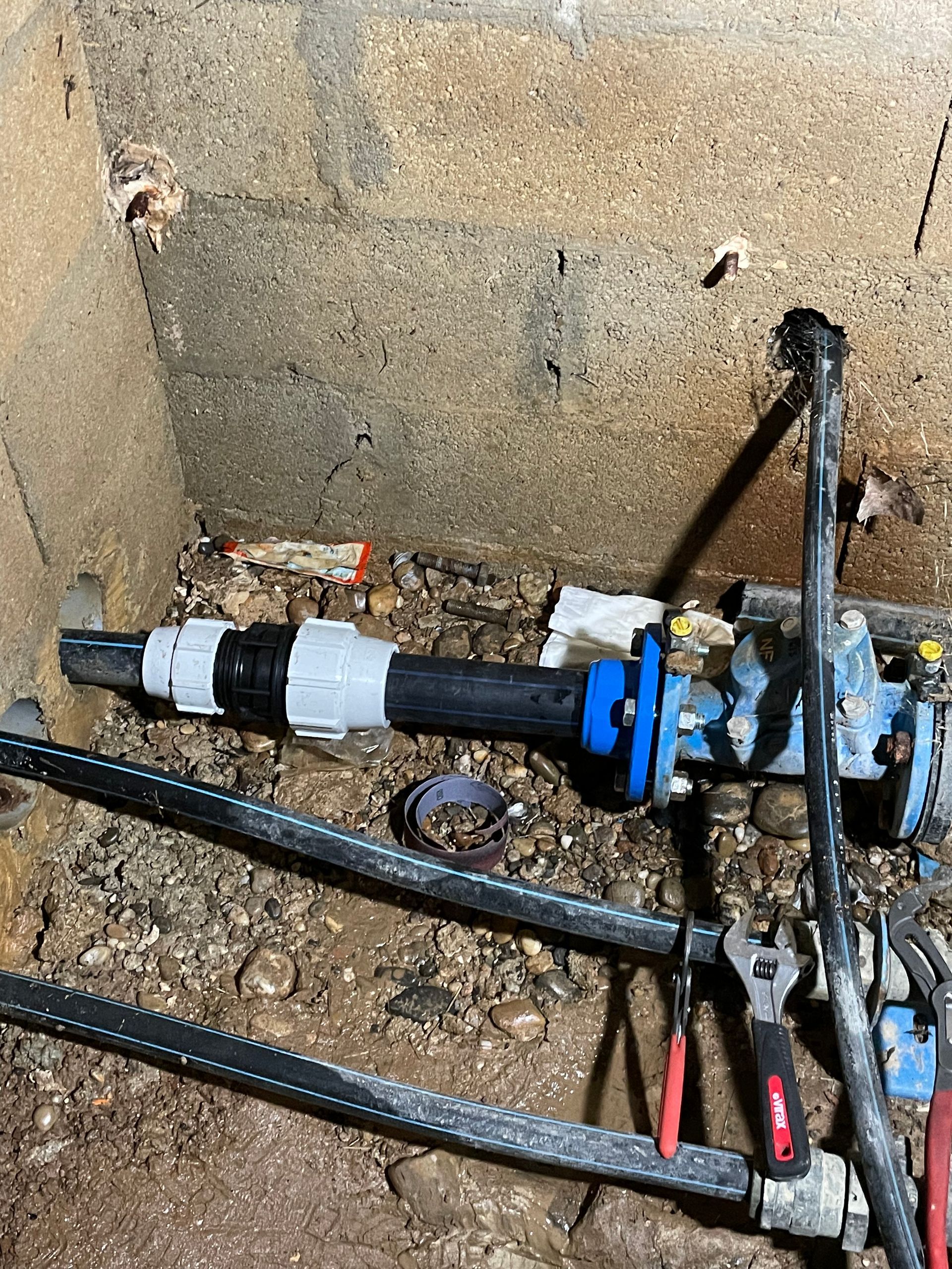 Tuyaux et raccords dans une enceinte en béton.