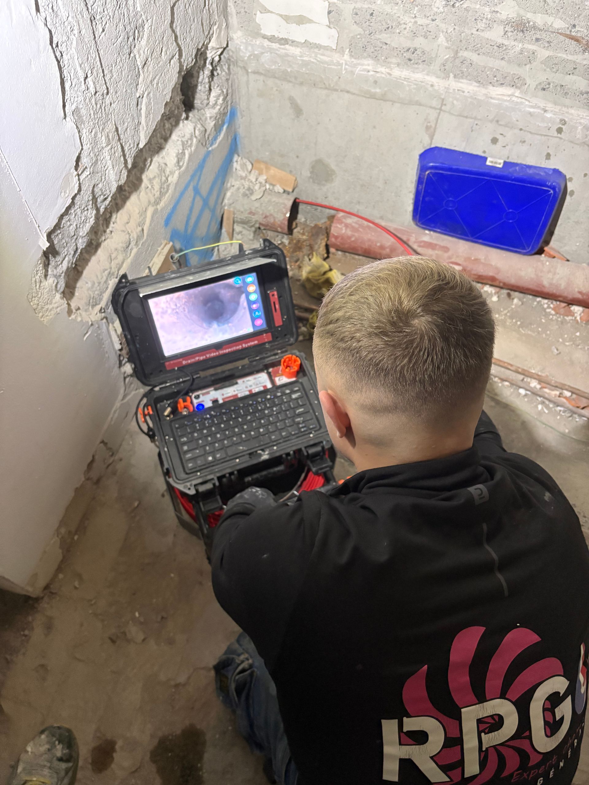 Une personne utilise une caméra pour inspecter la plomberie d'un sous-sol.