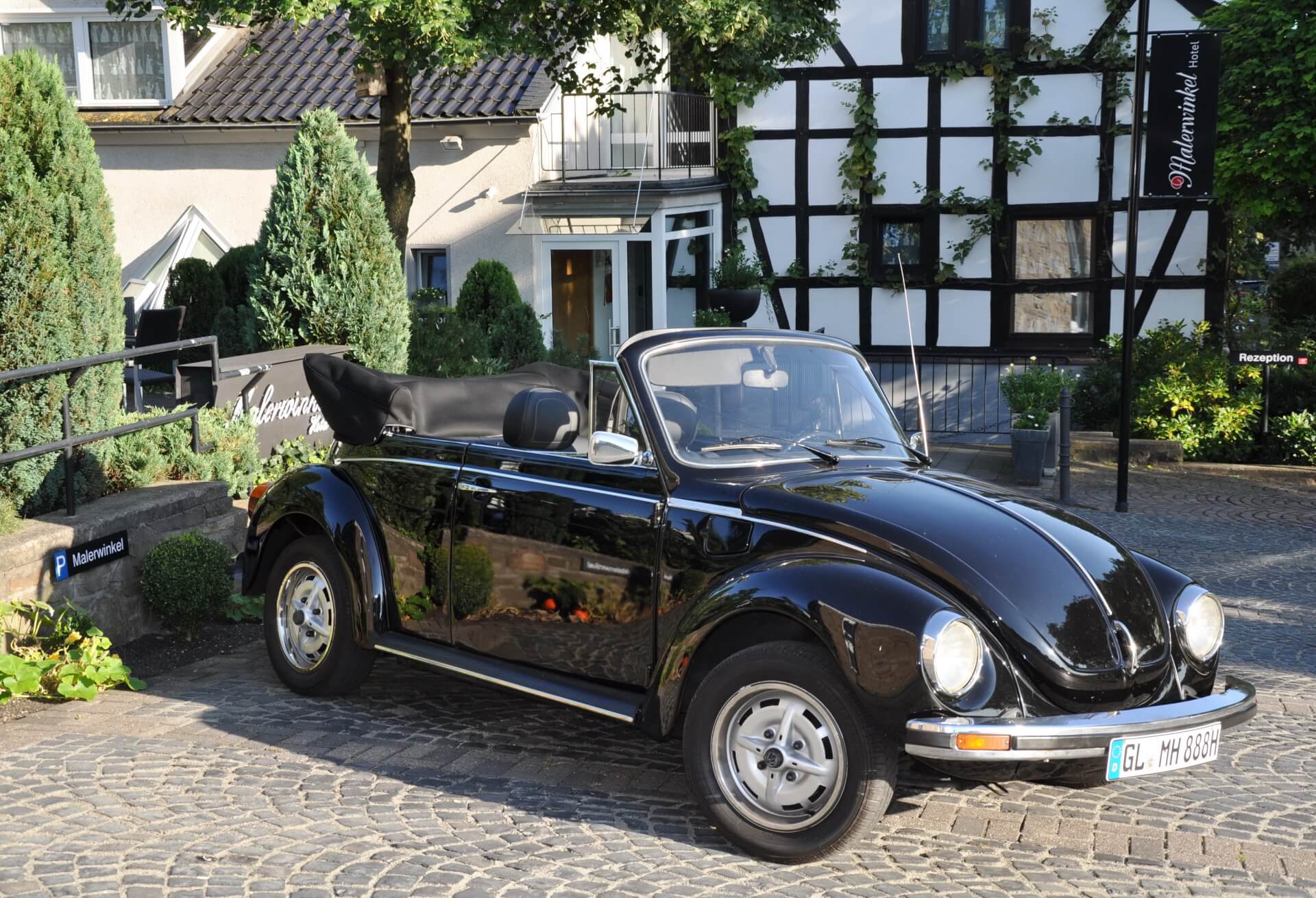 Ein schwarzes Käfer Cabrio steht vor einem Haus