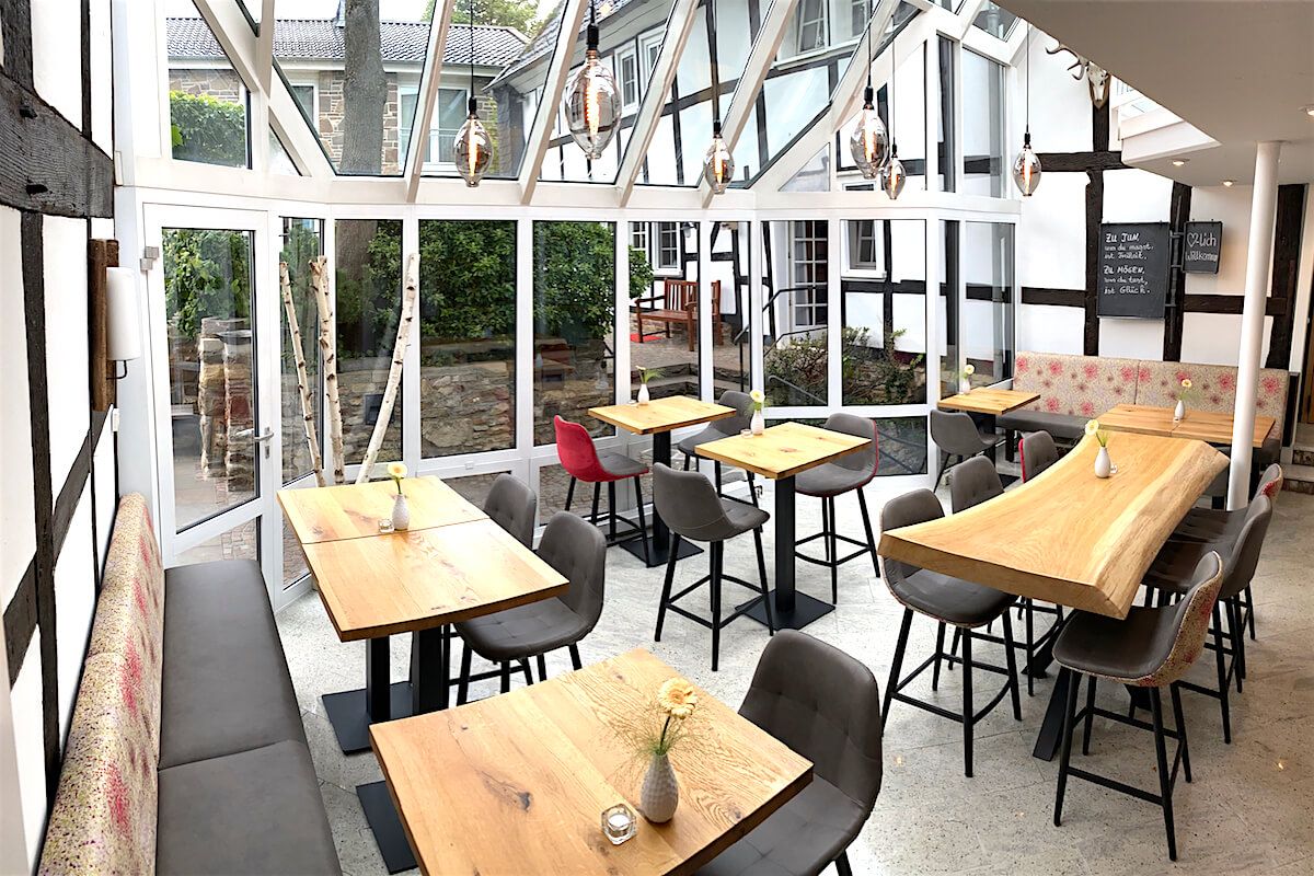 Ein Restaurant mit Tischen und Stühlen und vielen Fenstern.