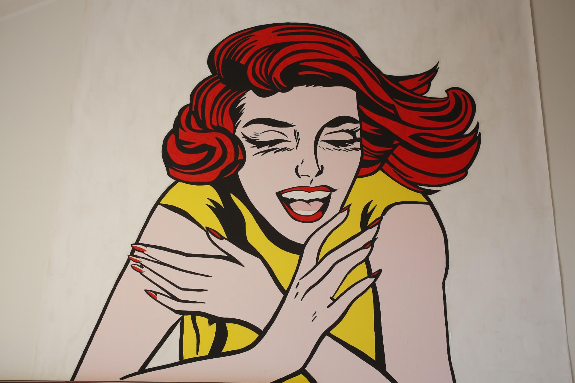 Eine Frau mit roten Haaren lacht mit geschlossenen Augen