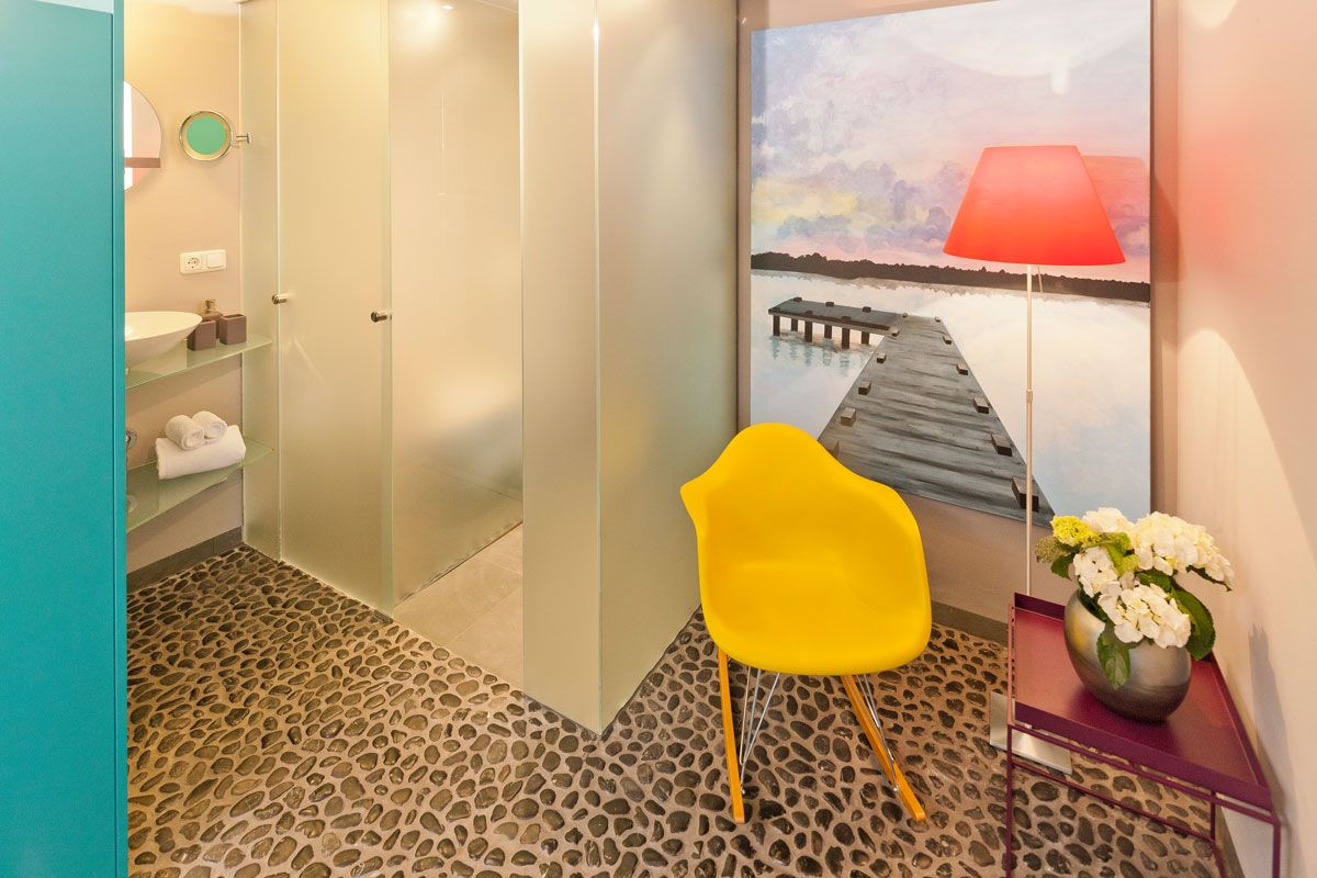 Ein Badezimmer mit einem gelben Stuhl und einem Gemälde an der Wand.