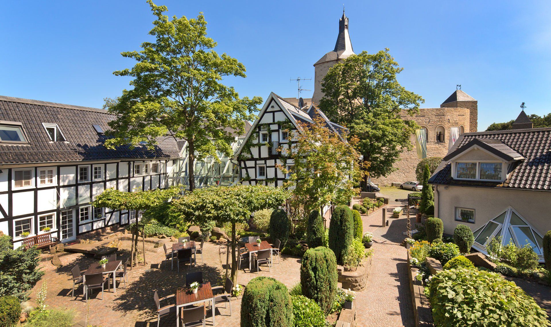 Eine Luftaufnahme eines Gartens mit Tischen und Stühlen vor dem Hotel.