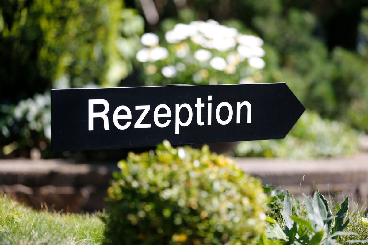 Ein schwarzes Schild mit dem Wort „Rezeption“ darauf