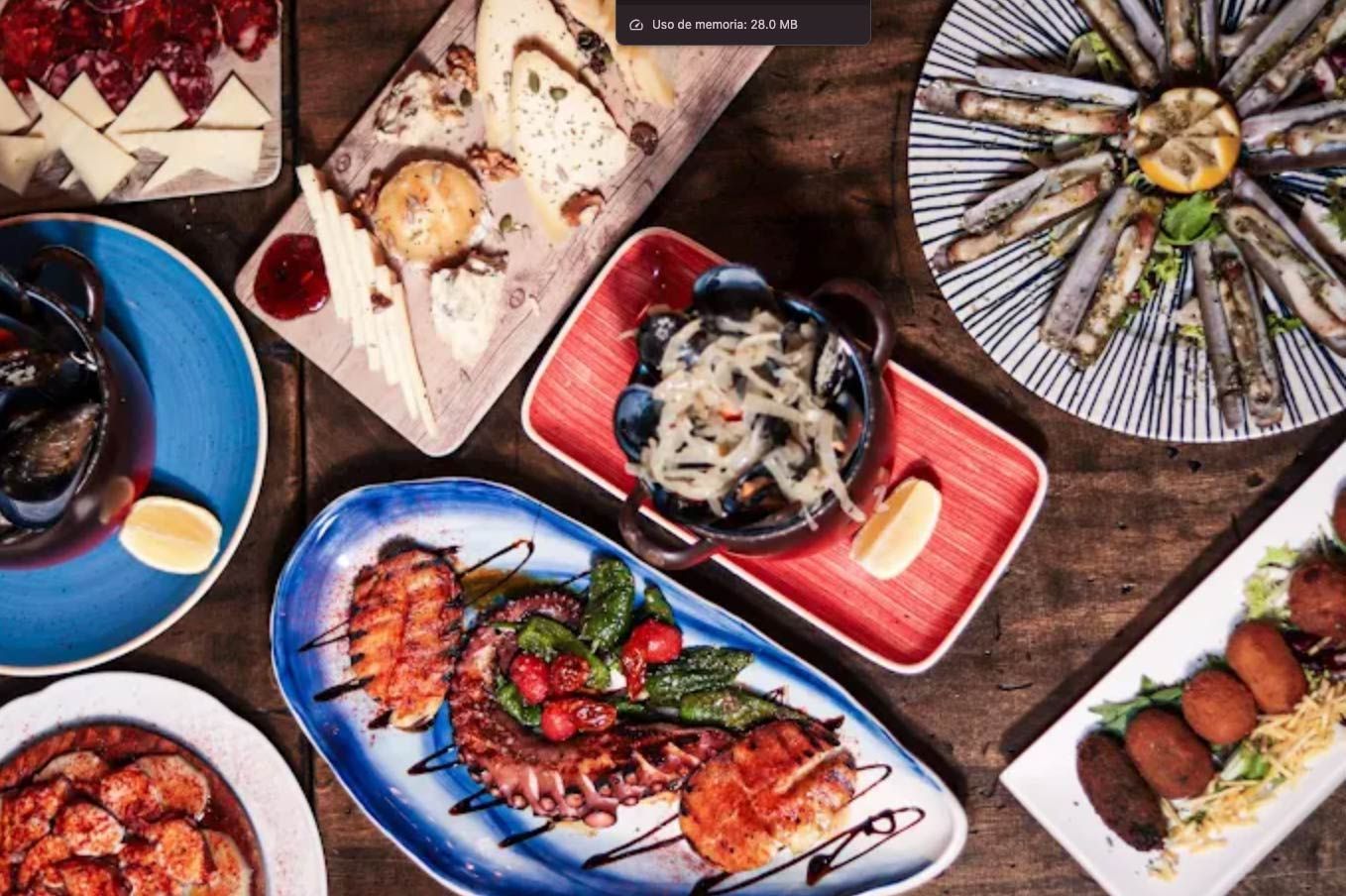 Varios platos de tapas españolas sobre una mesa de madera: mariscos, quesos y croquetas.