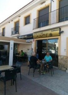 Un grupo de personas están sentadas en mesas afuera de un restaurante.
