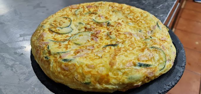 Una tortilla está sentada en un plato negro sobre una mesa.