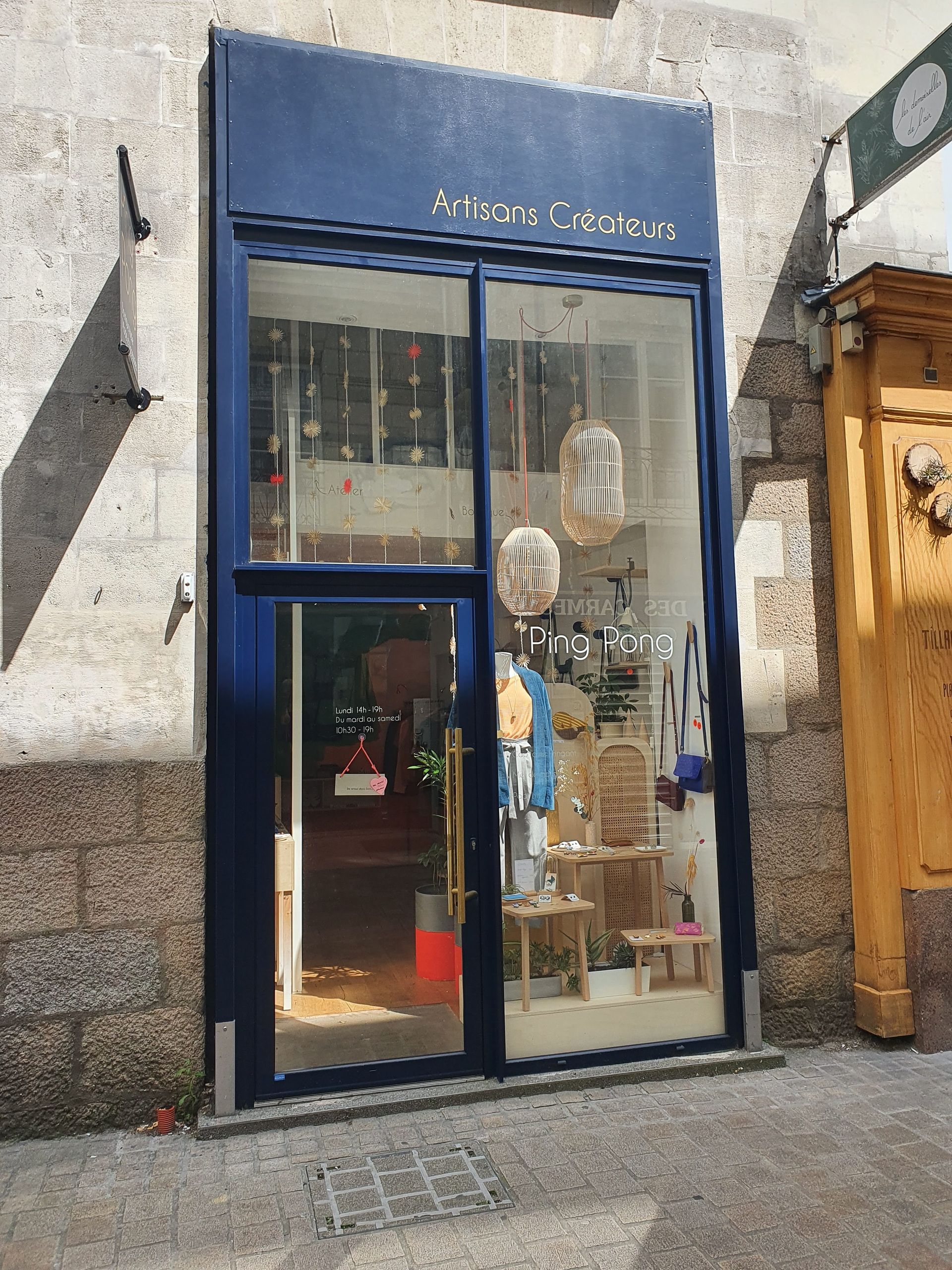 Boutique à encadrement bleu avec de grandes vitrines exposant divers articles.