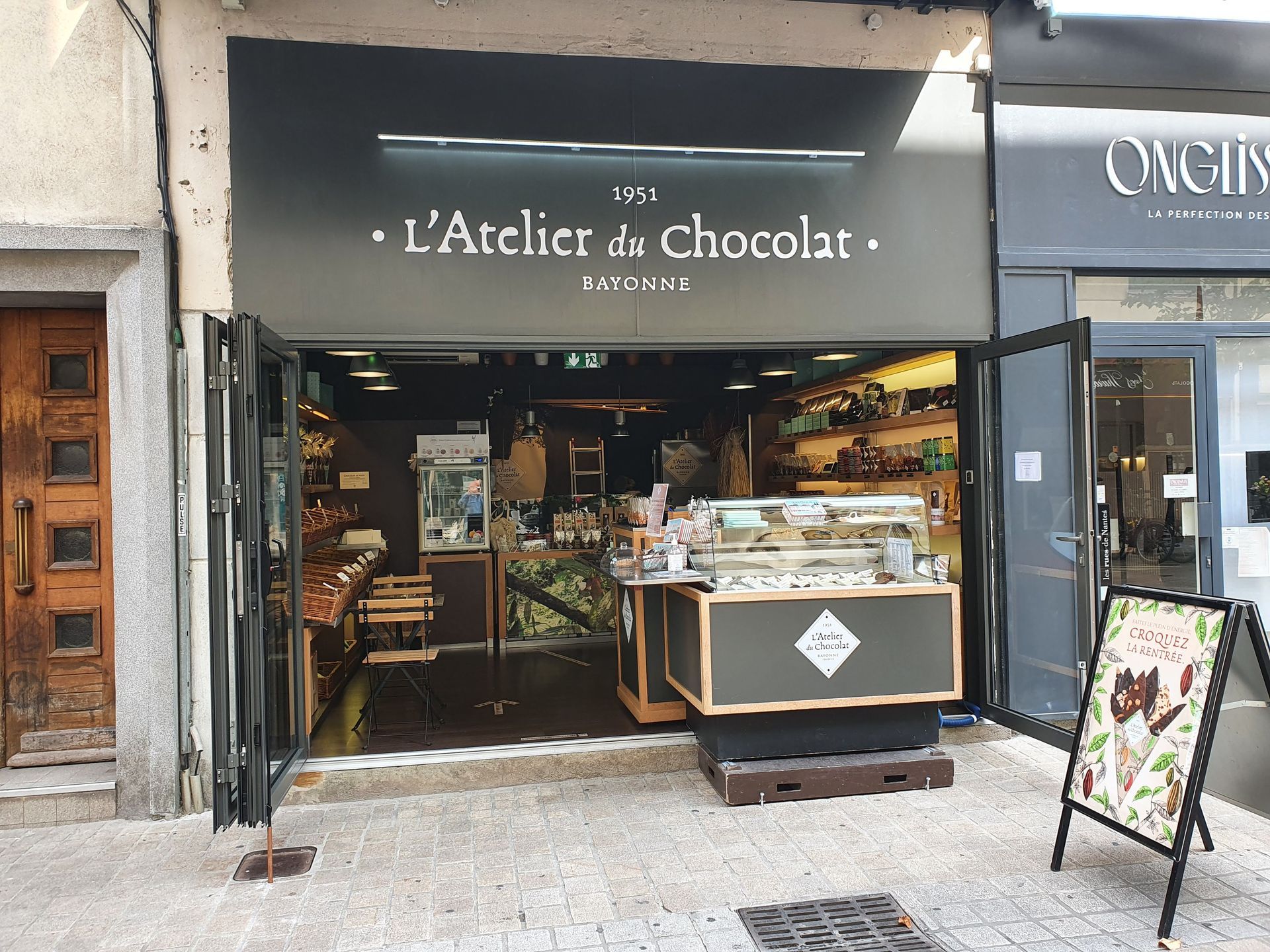 Façade de L'Atelier de chocolat avec portes ouvertes, présentant des produits.