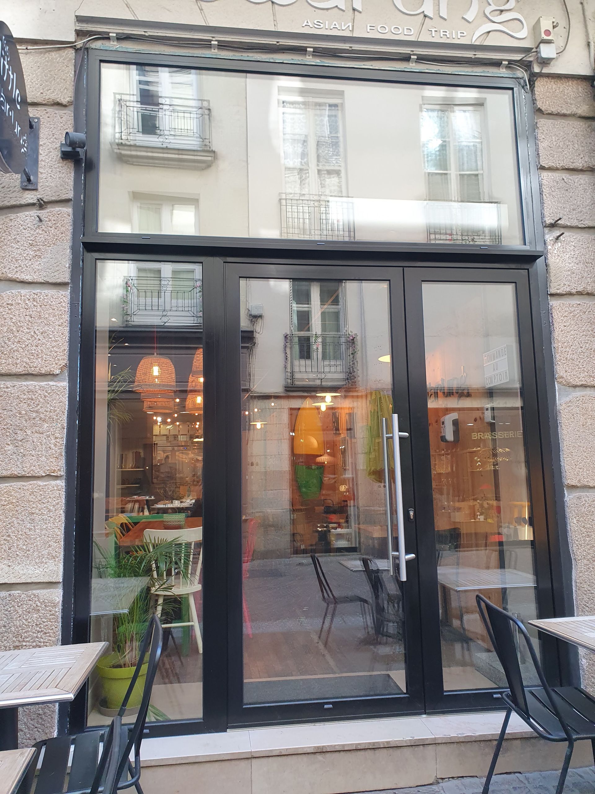 Portes et fenêtres vitrées à cadre noir reflétant les immeubles de l'autre côté de la rue.