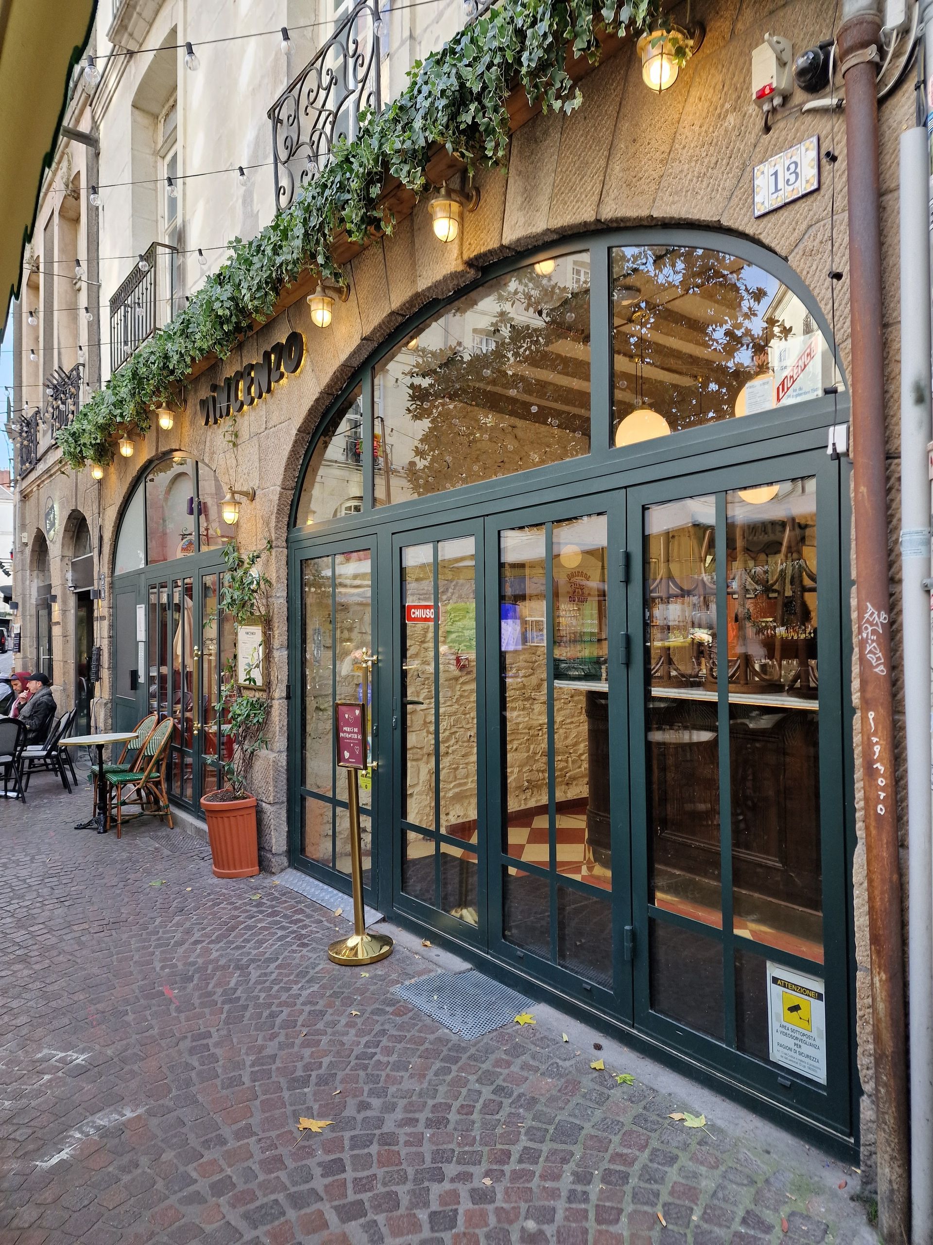 Extérieur d'un bâtiment avec son entrée voûtée, ses grandes fenêtres et sa terrasse.