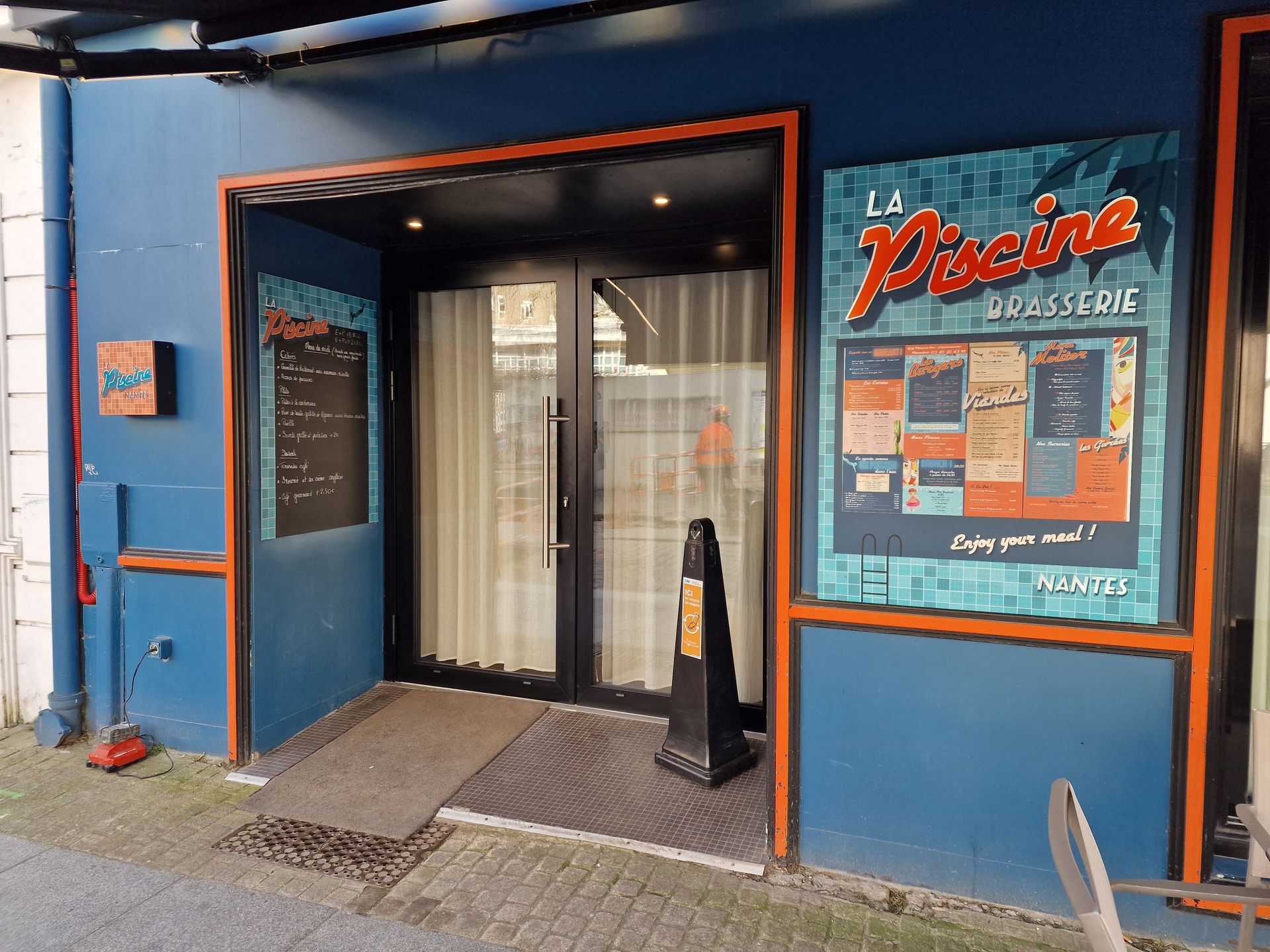 Entrée d'un bâtiment bleu avec enseigne.