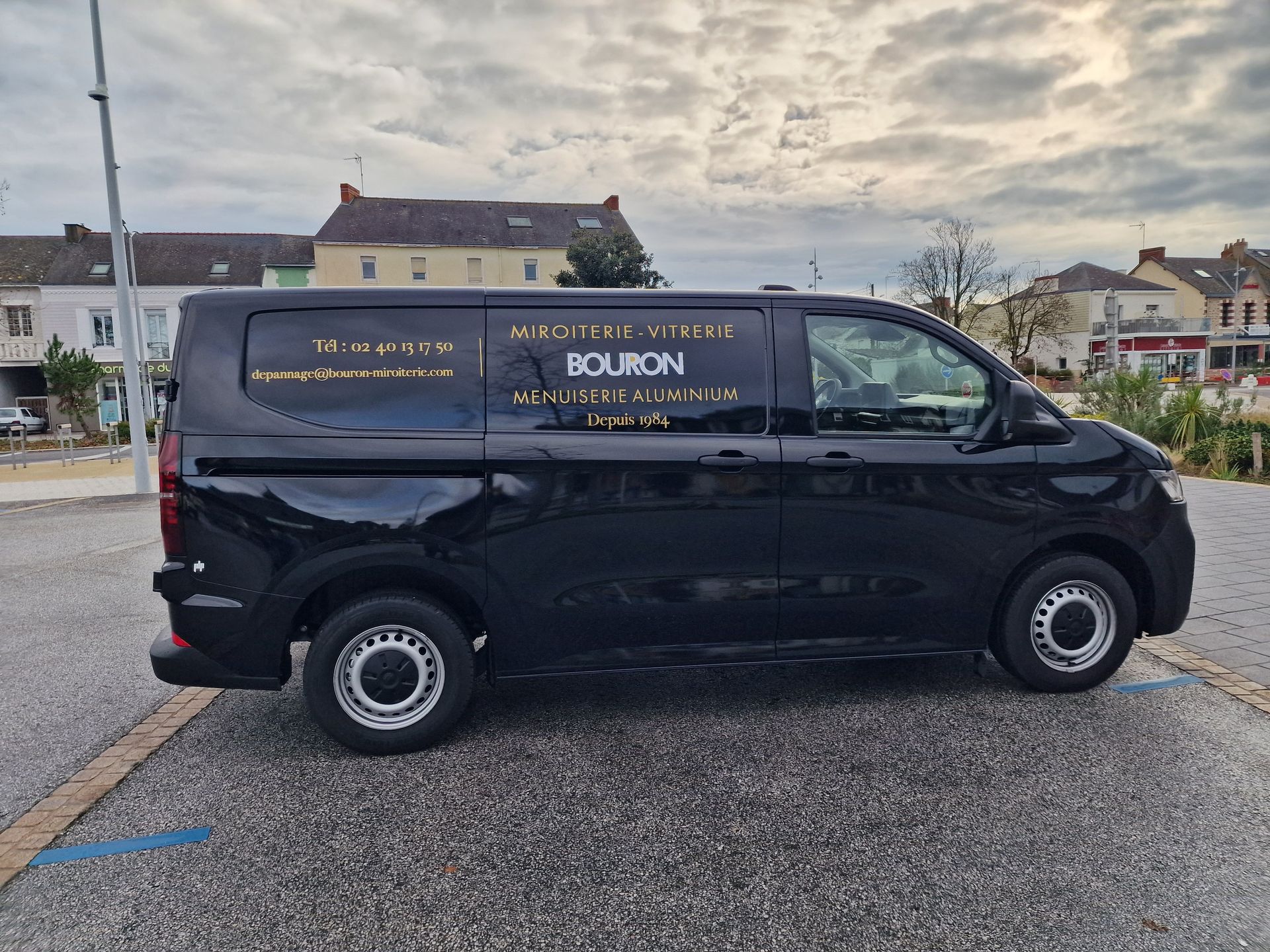 Camionnette livraison noire stationnée sur un parking.