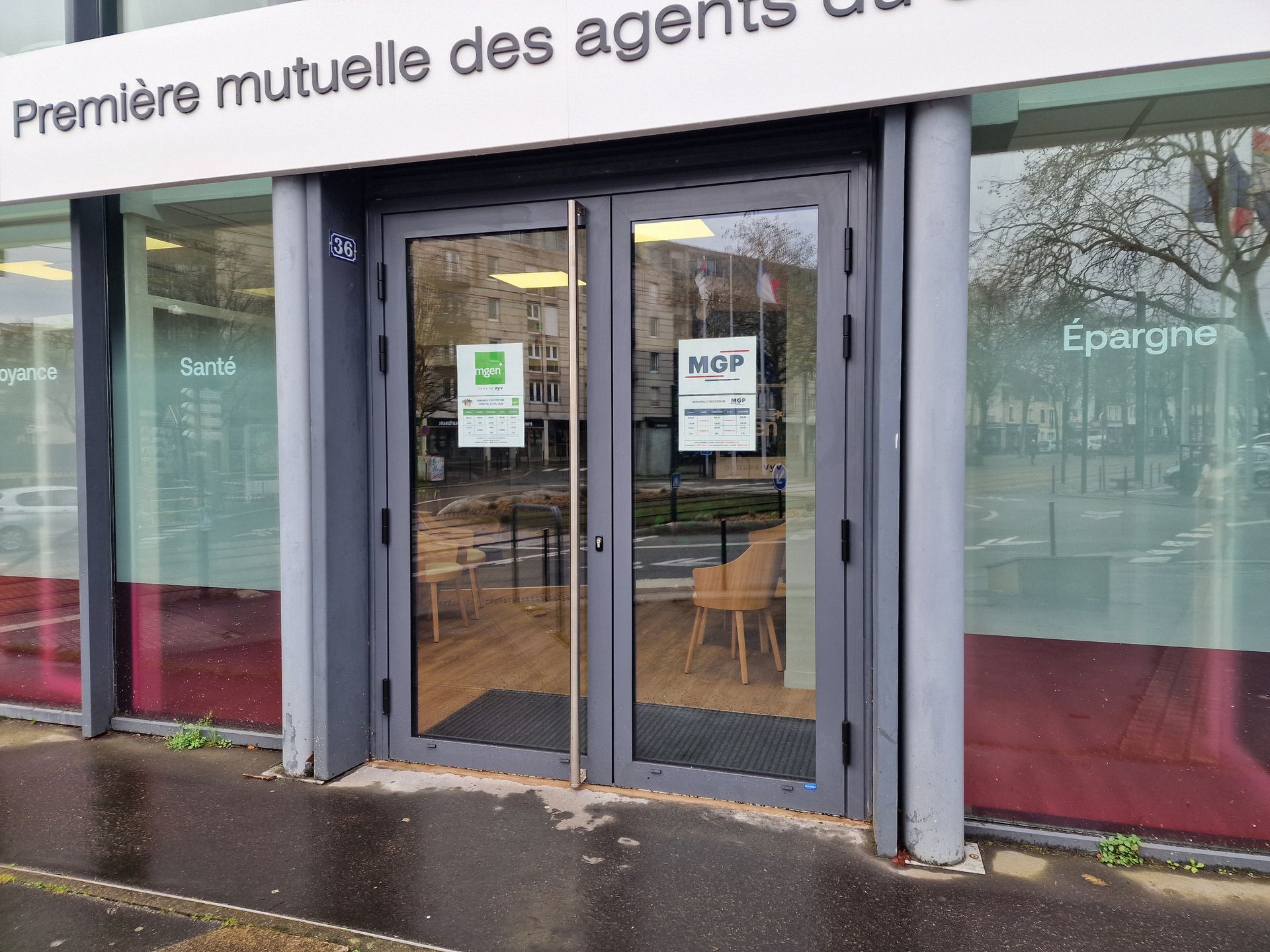 Extérieur d'un bâtiment avec portes vitrées, enseignes et nom de l'entreprise en haut.