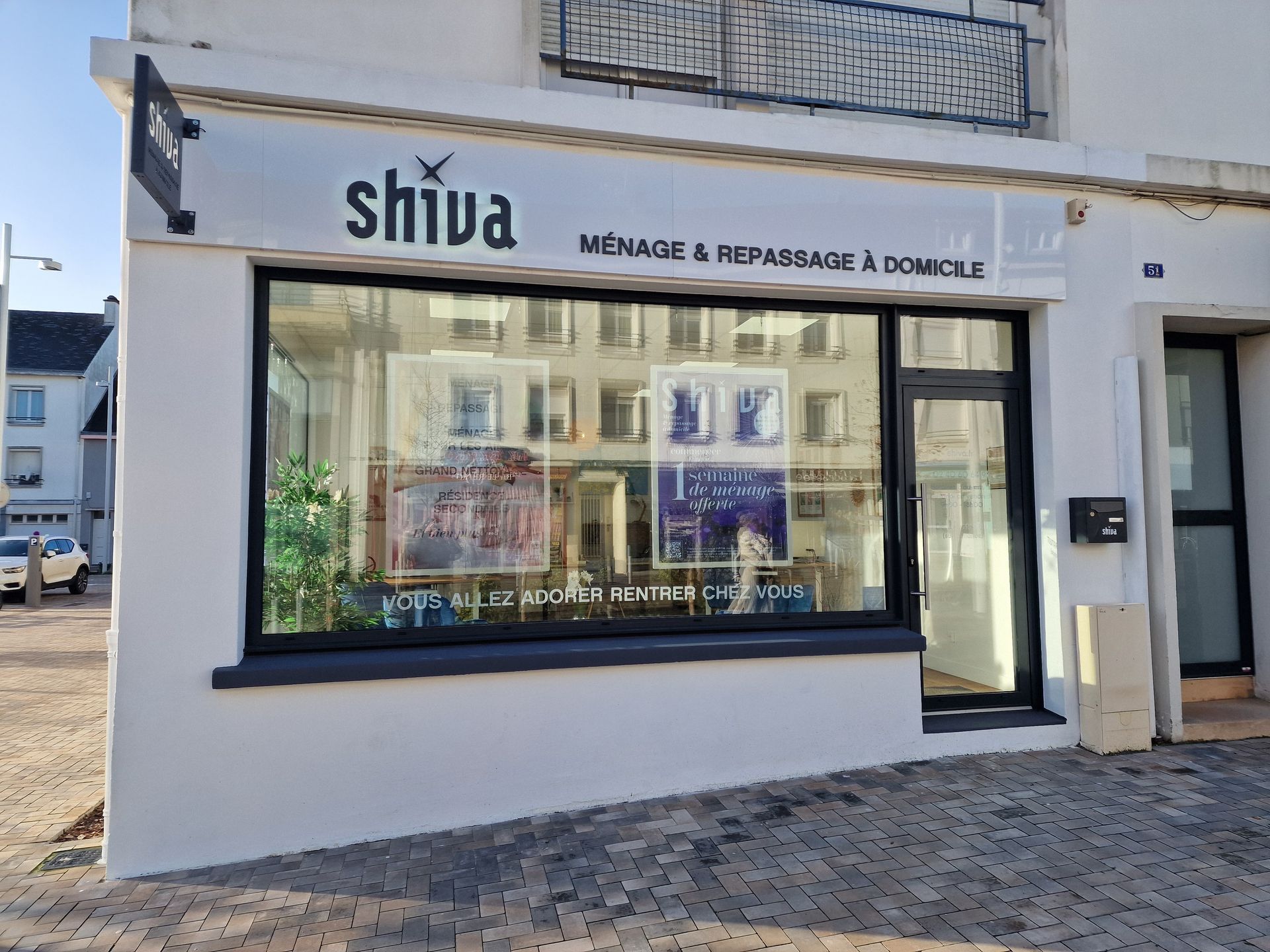 Extérieur d'une boutique avec une grande vitrine affichant des images, porte noire, petite enseigne.