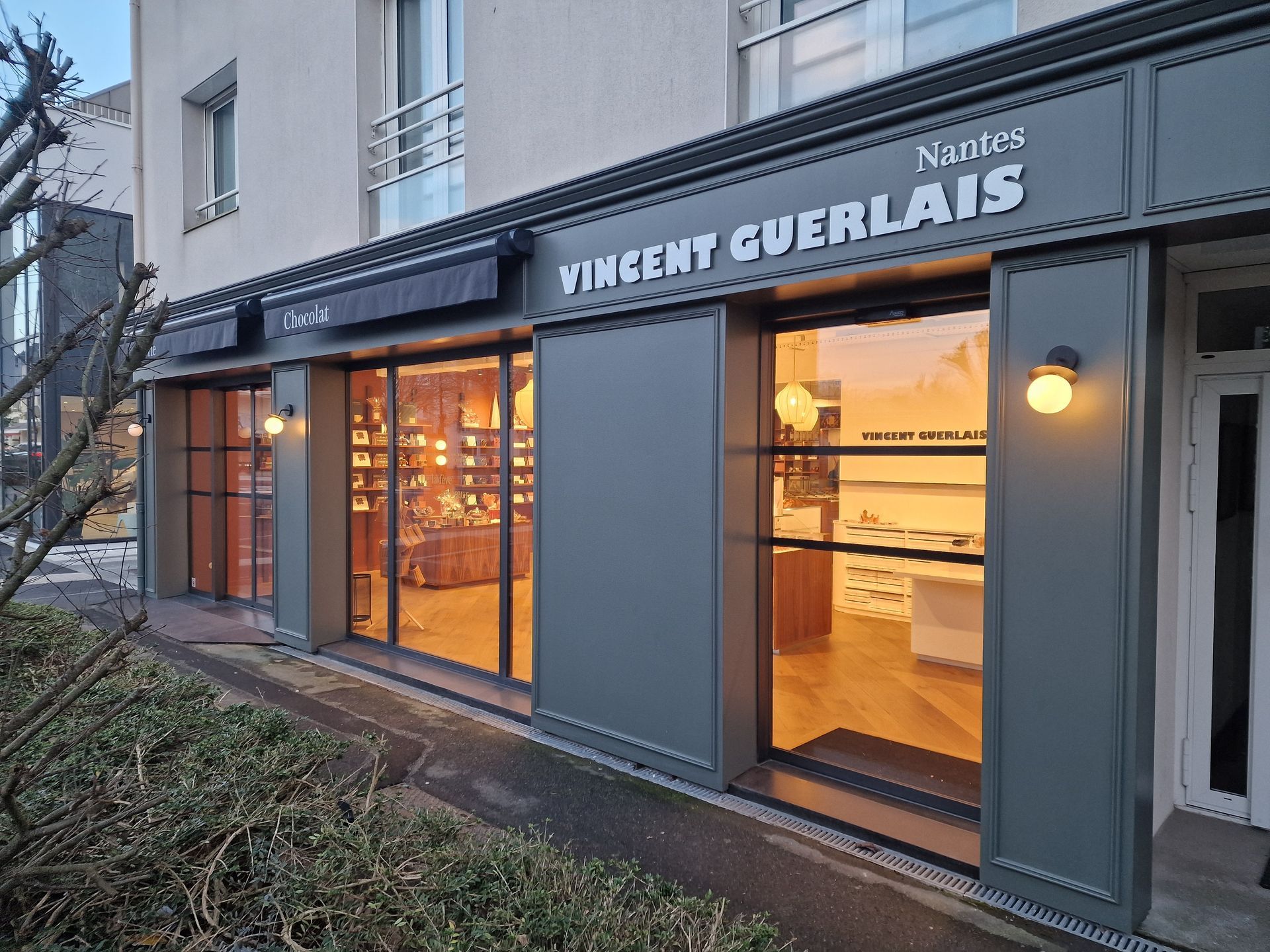 Extérieur d'une boutique avec vitrines et auvent sombre.