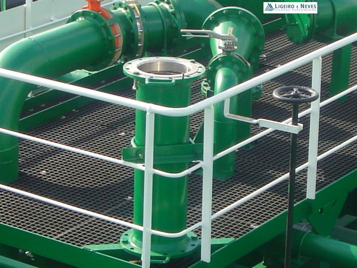 Tubos, válvulas e corrimãos verdes sobre uma plataforma metálica.