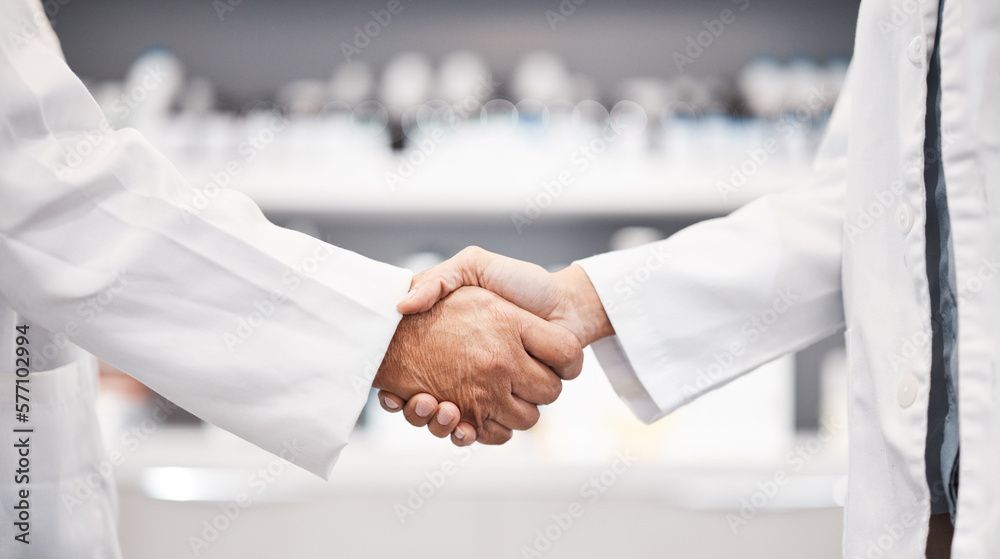 Zwei Personen in weissen Kitteln schütteln sich in einer Apotheke die Hände.