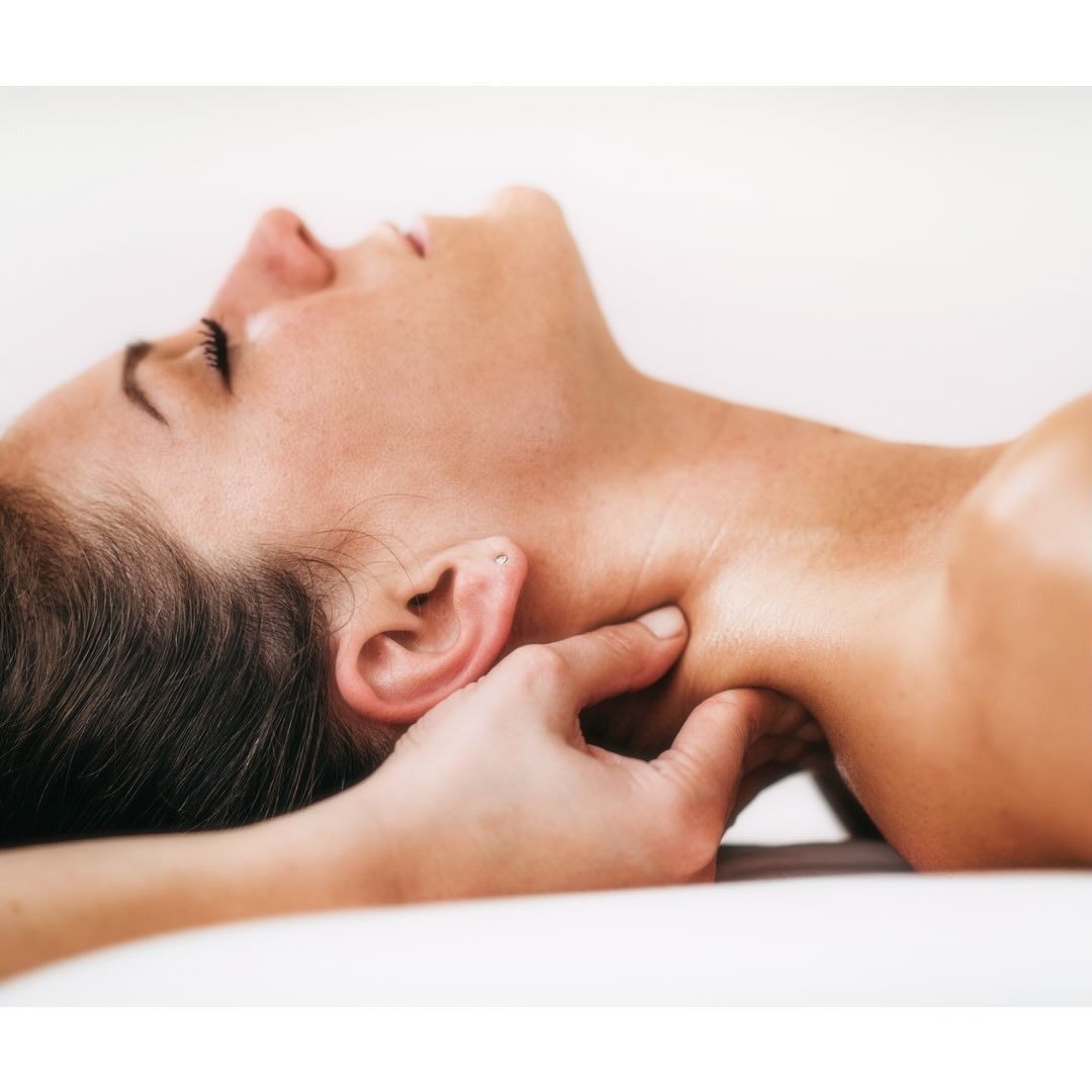 Frau erhält Nackenmassage, liegt mit geschlossenen Augen da, Hand übt Druck aus.