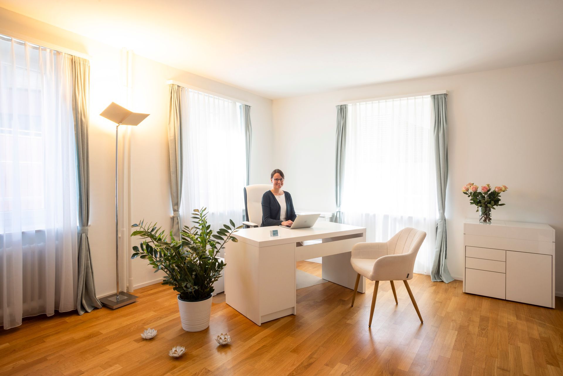 Zimmer mit medizinischer Ausrüstung und einer Behandlungsliege. Weisse und grüne Wände, Holzboden und Fenster.