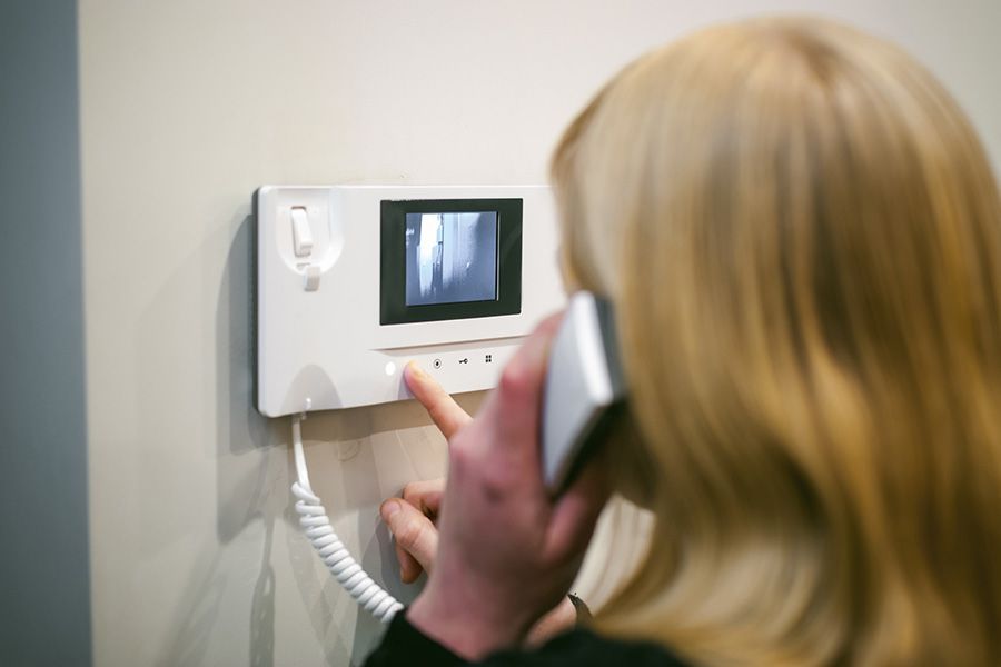 Eine Frau telefoniert vor einer Videotürklingel.