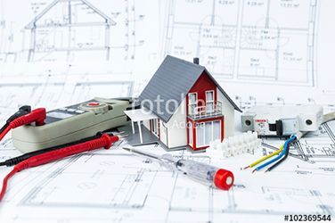 Auf einem Bauplan steht ein Modellhaus mit elektrischer Ausrüstung.