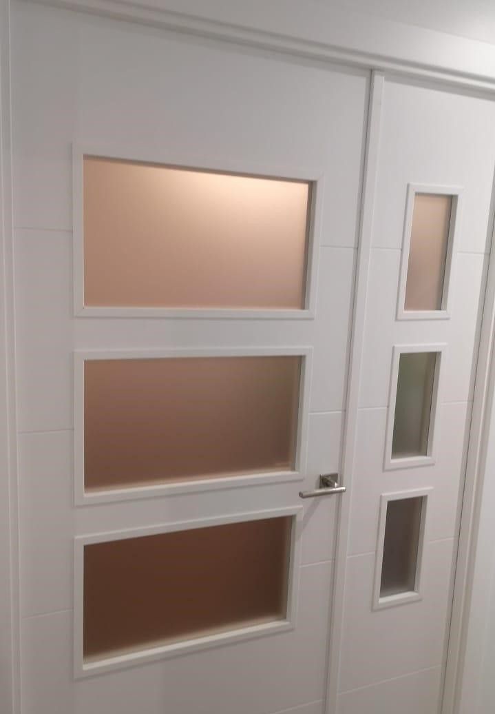 Puerta interior blanca con paneles de vidrio esmerilado.