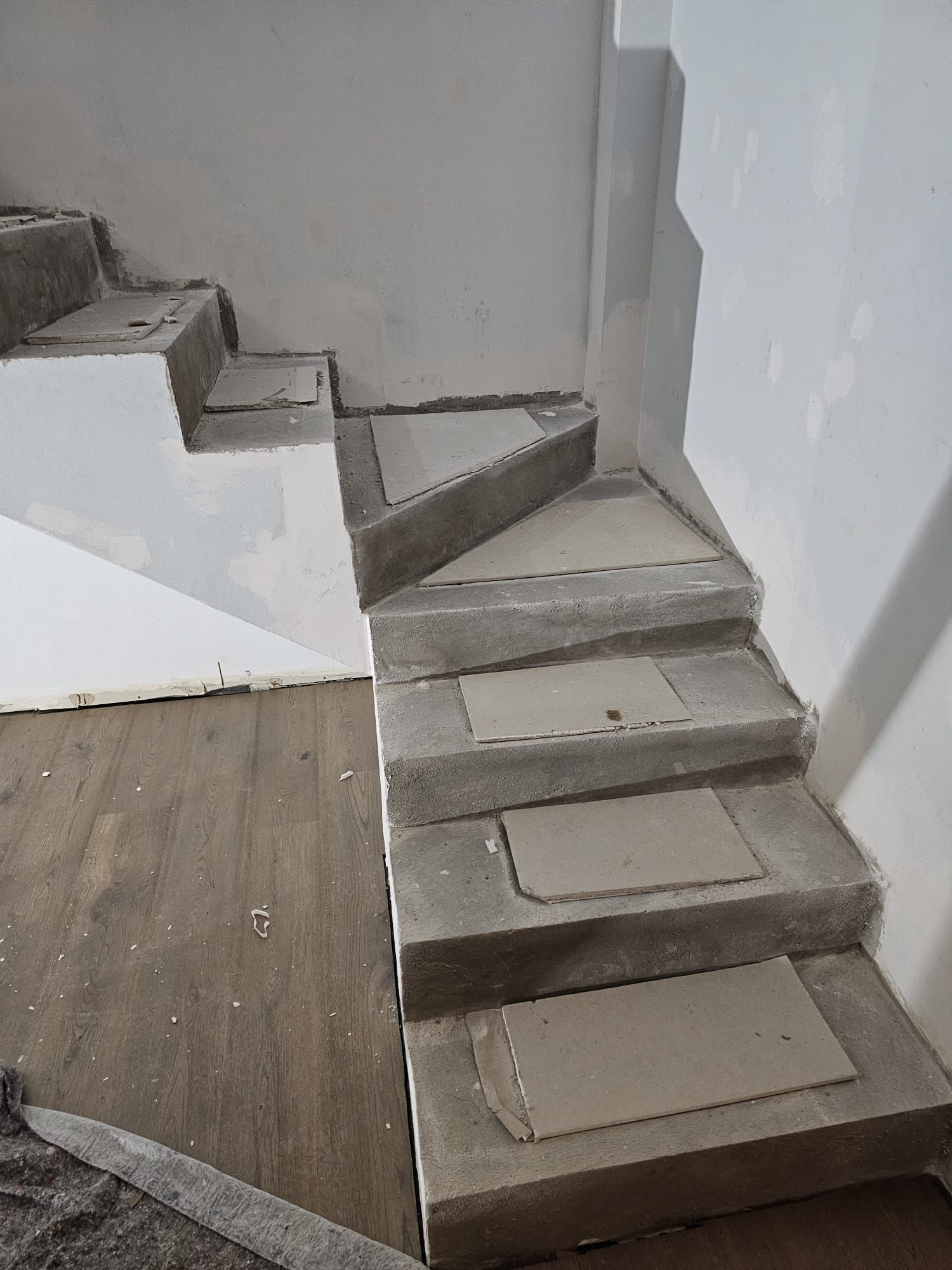 Escalera de hormigón en construcción, escalones, paredes blancas, suelo de madera.
