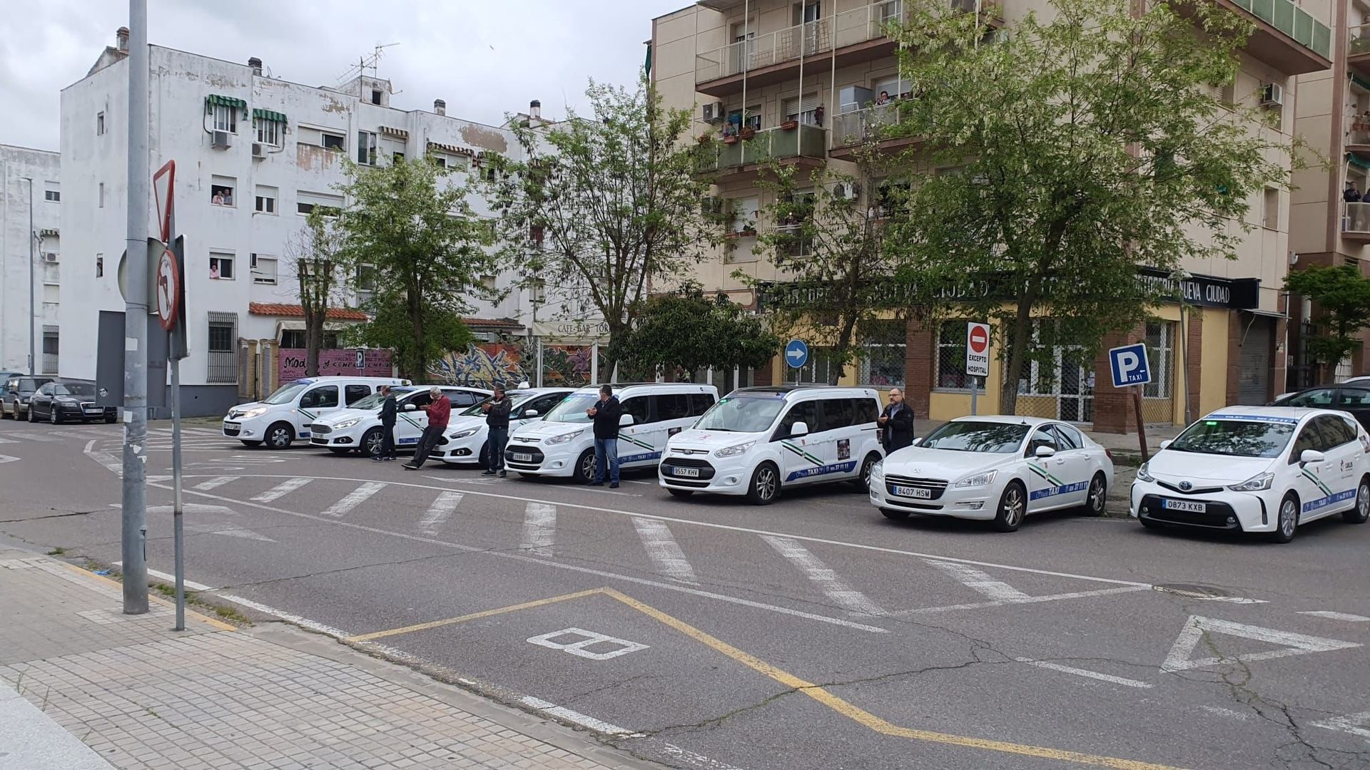 Una fila de coches están estacionados en un estacionamiento frente a un edificio.