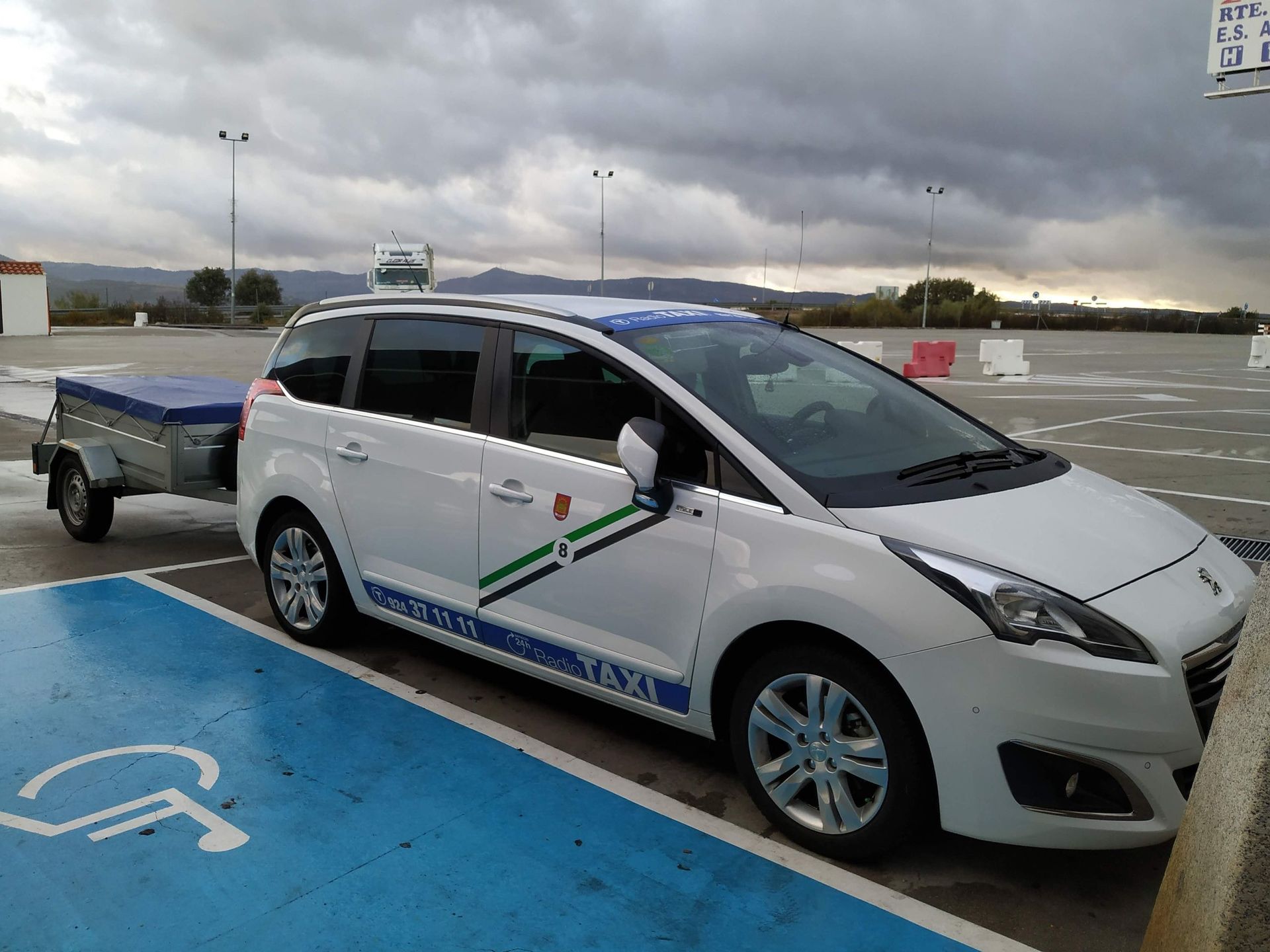 Un taxi blanco está estacionado en un lugar de estacionamiento para discapacitados.