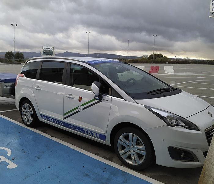 Un taxi blanco está estacionado en un lugar de estacionamiento para discapacitados.