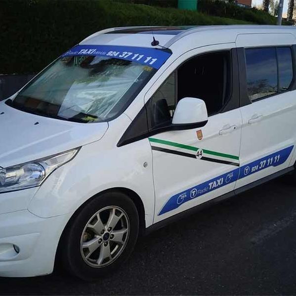 Una camioneta blanca con una pancarta azul que dice taxi.
