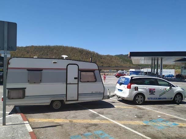Una caravana está siendo remolcada por un automóvil en un estacionamiento.