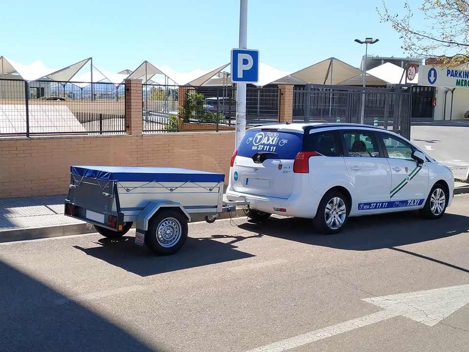 Un taxi está estacionado al lado de un pequeño remolque.