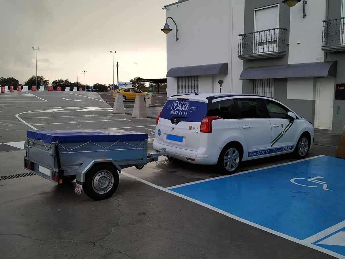 Una camioneta blanca con la palabra taxi en la parte trasera está estacionada en un lugar de estacionamiento para discapacitados.