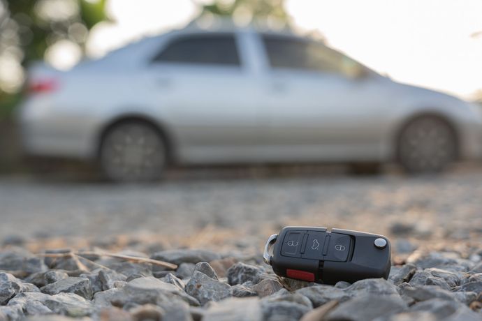 Une clé de voiture au sol devant une voiture