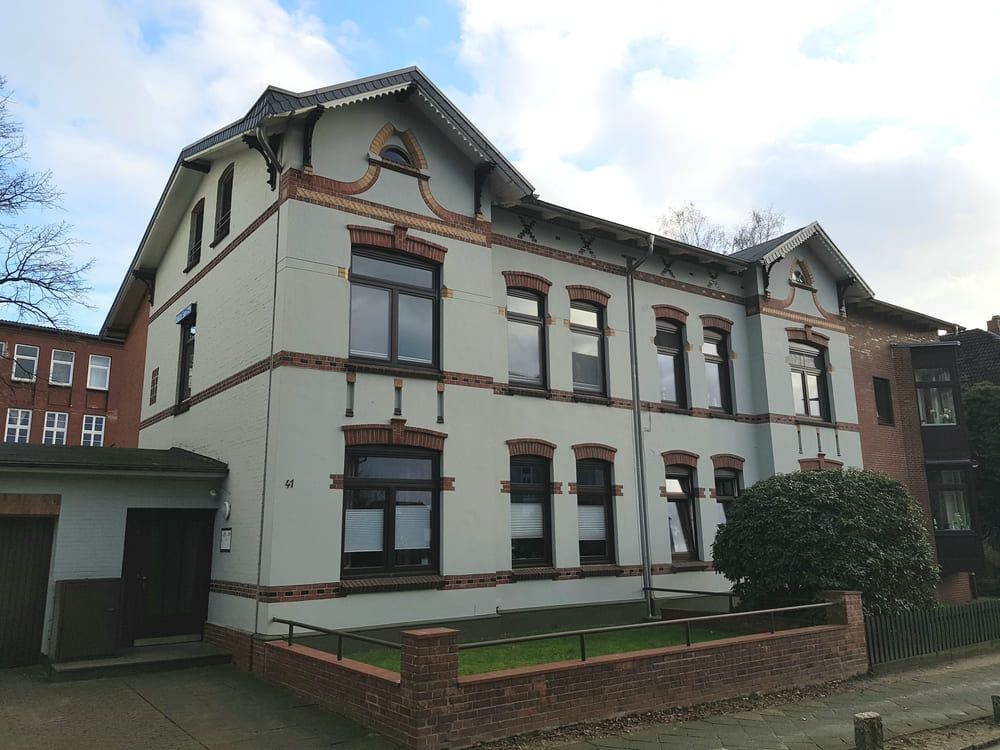 Ein großes weißes Gebäude mit vielen Fenstern und einer Backsteinmauer.