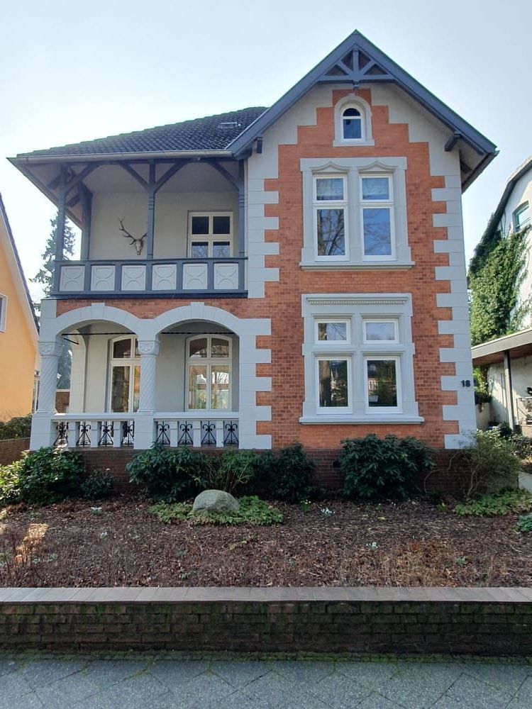 Ein großes orange-weißes Backsteinhaus mit Balkon