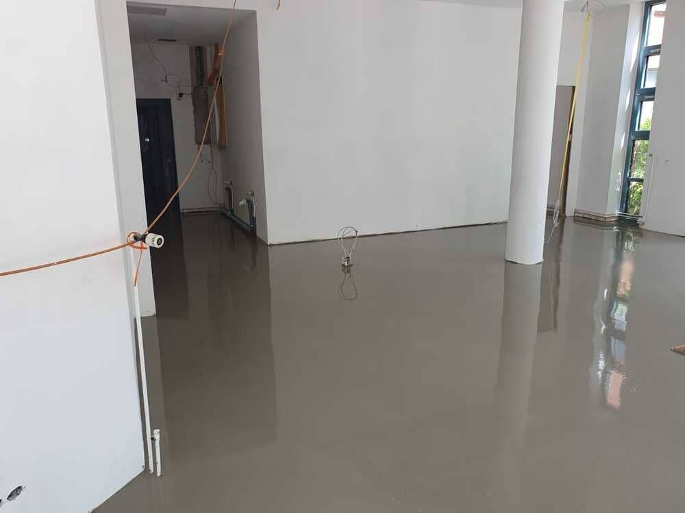 Ein großer leerer Raum mit Betonboden und weißen Wänden.