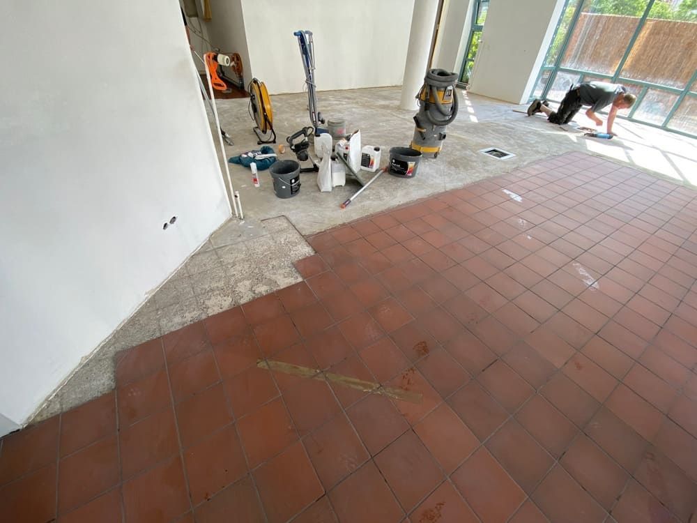 Ein Mann kniet in einem Raum auf einem gefliesten Boden.