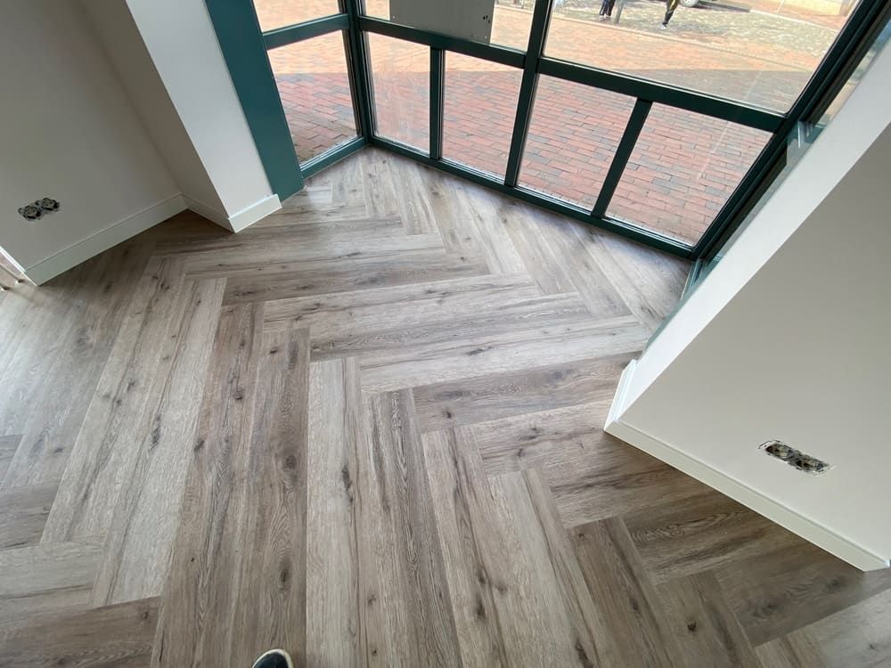 Eine Person steht auf einem Holzboden in einem Raum mit einem großen Fenster.