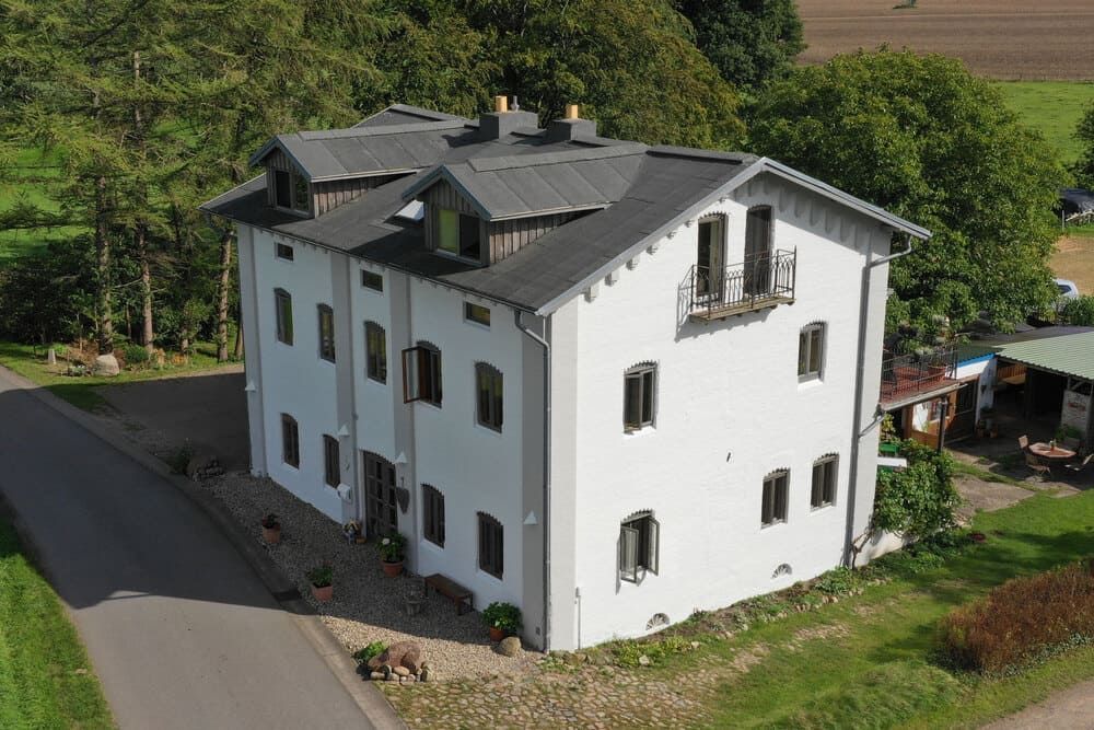 Eine Luftaufnahme eines großen weißen Hauses, umgeben von Bäumen und Gras.