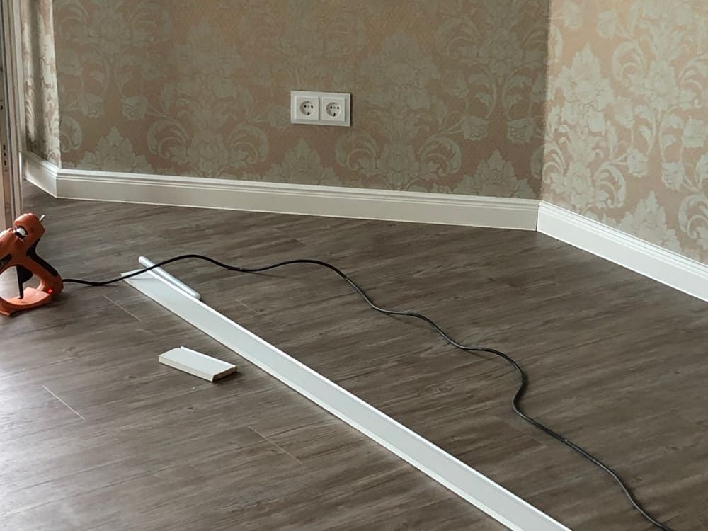 Ein Raum mit einem Holzboden und einer Lampe auf dem Boden.