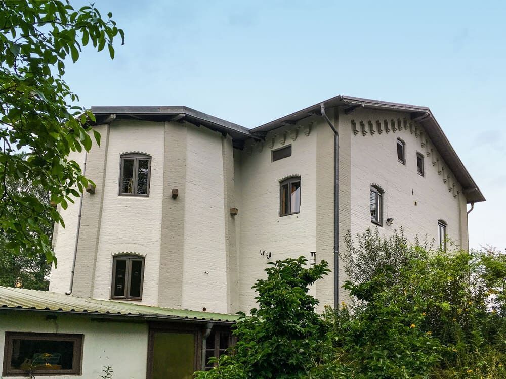 Ein großes weißes Gebäude ist von Bäumen und Büschen umgeben