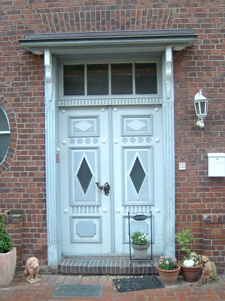 Ein Backsteingebäude mit einer weißen Tür und Topfpflanzen davor