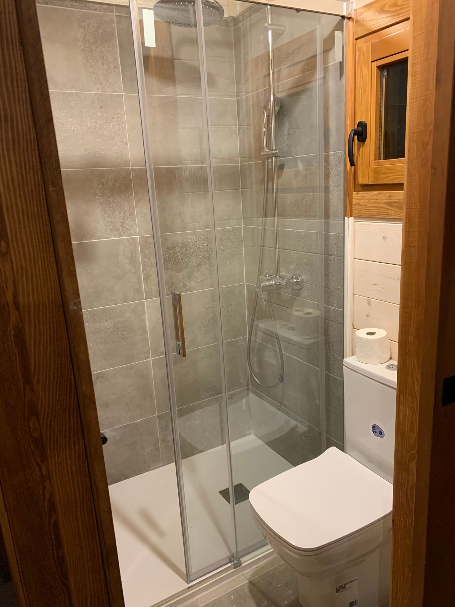 Un baño con inodoro, ducha y puerta de cristal.