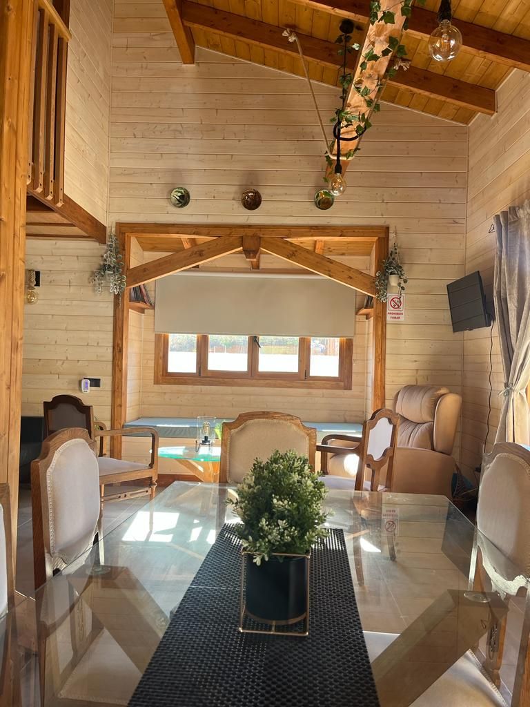 Una sala de estar con una mesa de cristal y sillas y un jarrón con flores sobre la mesa.